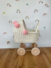 Load image into Gallery viewer, Wicker pram with bow, tall dolls pram, bow and bedding included. Cream/ off white pram with light pink pom-poms and bedding of your choice.
