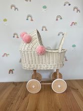 Load image into Gallery viewer, Wicker pram with bow, tall dolls pram, bow and bedding included. Cream/ off white pram with light pink pom-poms and bedding of your choice.
